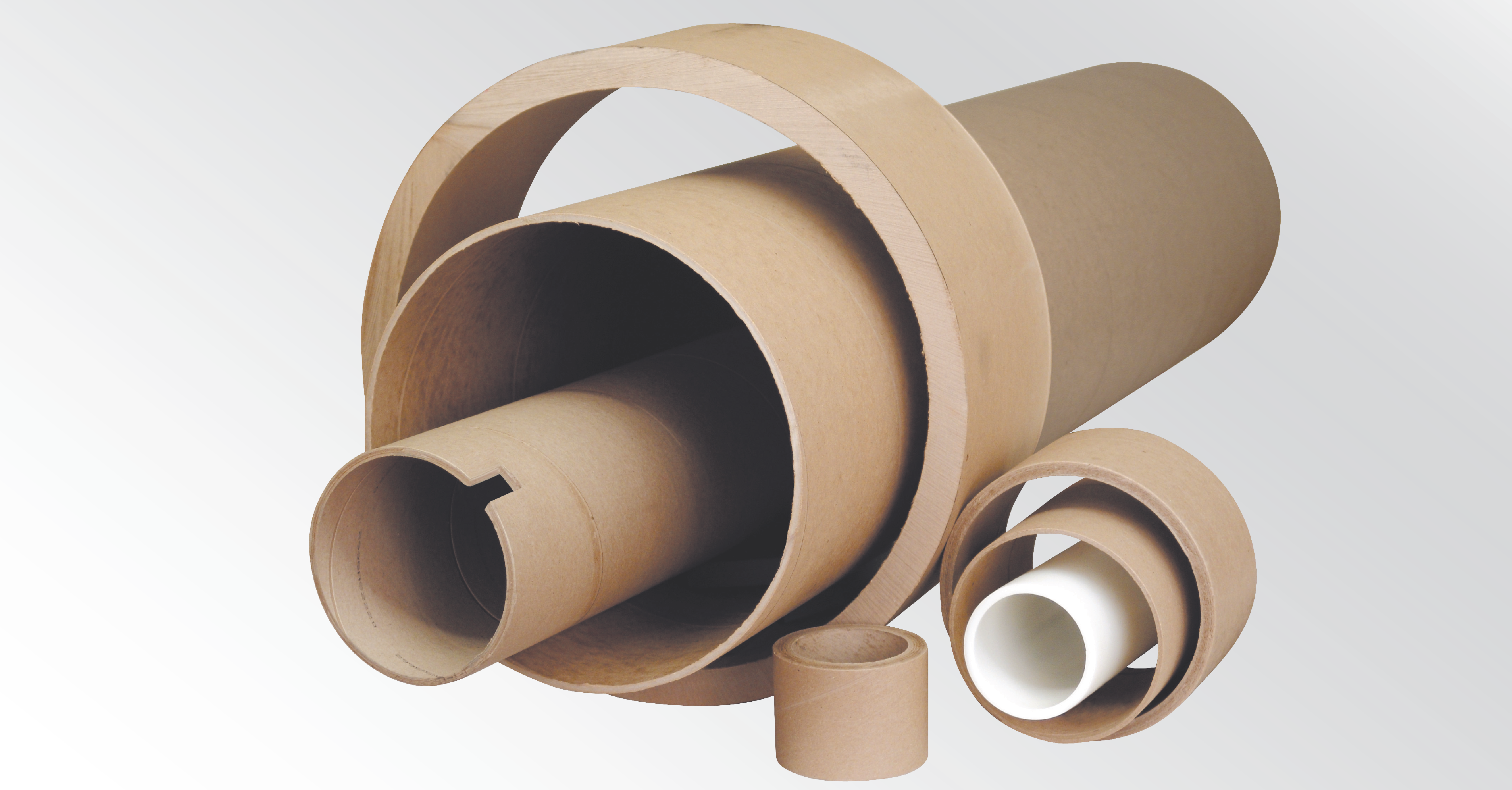 Assortment of paper cores in various diameters and lengths alongside a plastic core, illustrating different core sizes used in converting applications