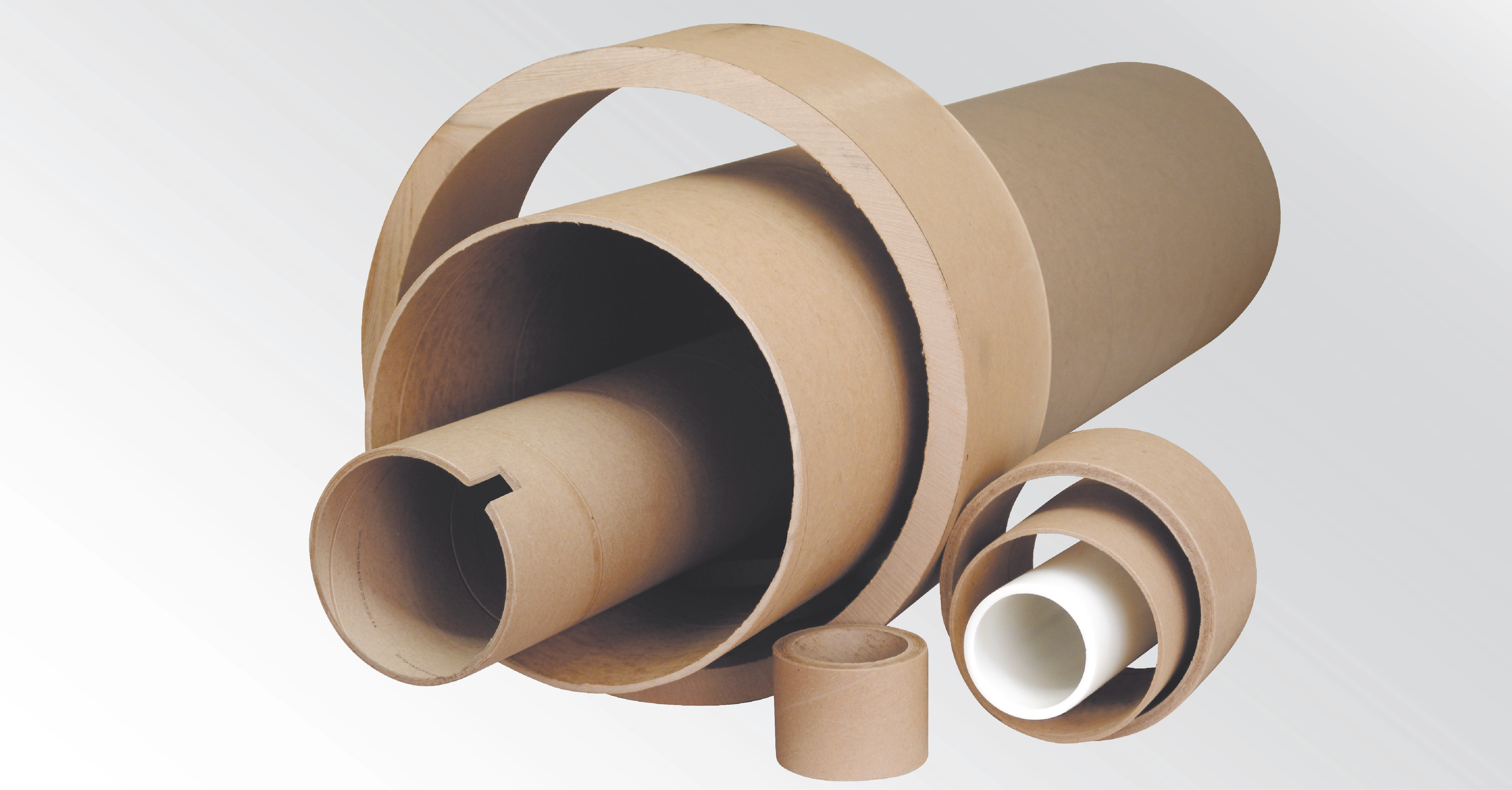 Assortment of paper cores in various diameters and lengths alongside a plastic core, illustrating different core sizes used in converting applications